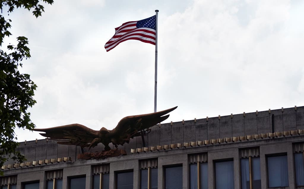 An eagle gracefully soars through the air above a towering building.